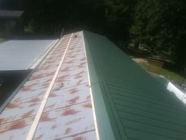 Old rusted panels beside newly installed green metal roofing — Wind Damage Roof Repair by Roofing Brothers in Hebron