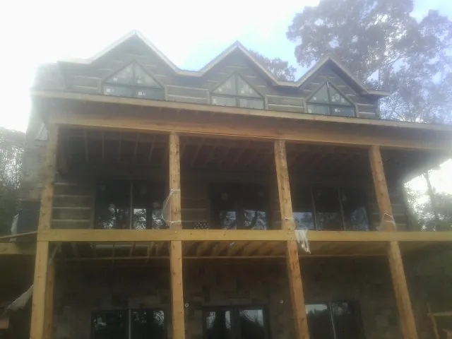 Dormers and porch framing on a large log home under construction — Roof Coating work by our crew in Hebron